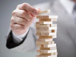 Planning, risk and strategy in business, businessman gambling placing wooden block on a tower