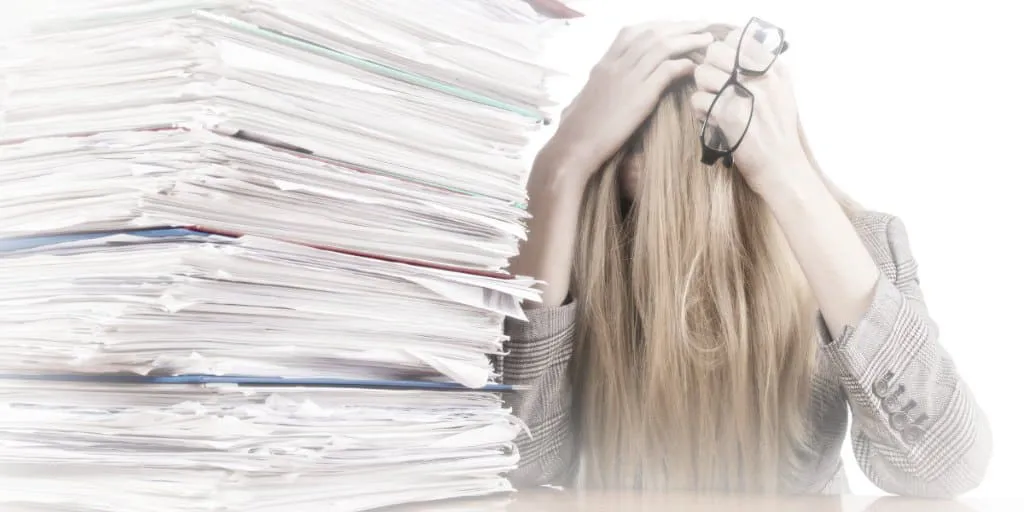 large stack of documents, women holding her head in stress